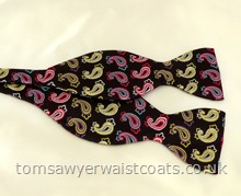 A multicoloured paisley patterned black silk self tie bowtie. Adjustable neckband, available in Men's size only (fits up to 18'' collar). Includes tying instructions.Made in the UK. This product is not made in our own workroom, but we were so impressed with the value of this bowtie that we decided to add it to our range. Neckwear Style- Self Tie Bowtie- Fabric- Silk- Colour- - Blue/magenta/lime/purple/white on black-